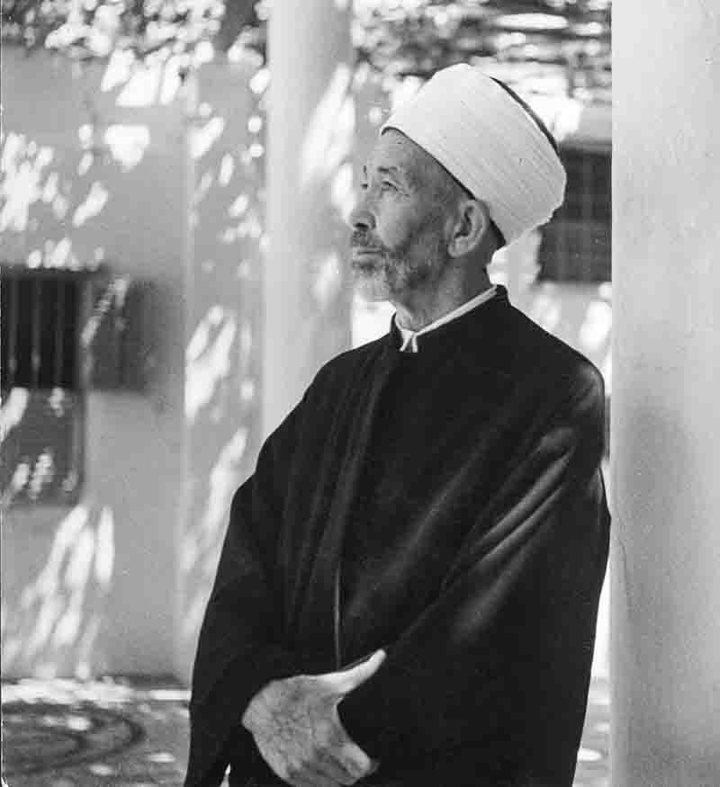 An elderly man wearing a white turban stands confidently in Haji Bani Hammam, Arcades and Religious Burial Place in the Old City in Baku, Azerbaijan.