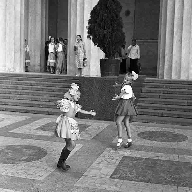 Two Belarusian performing a dance in front of a building.