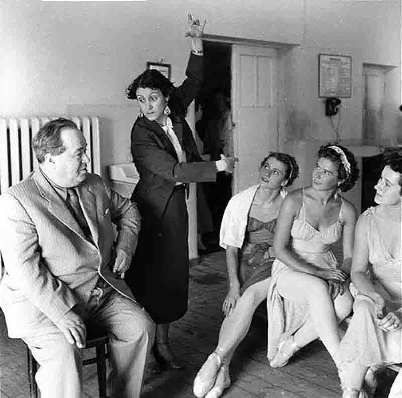 A man sits in a chair surrounded by women, who are attentively listening and participating in the discussion.