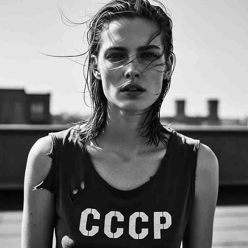 A black and white, head-on, medium shot of a model wearing a distressed tank top with the letters CCCP printed on the chest.