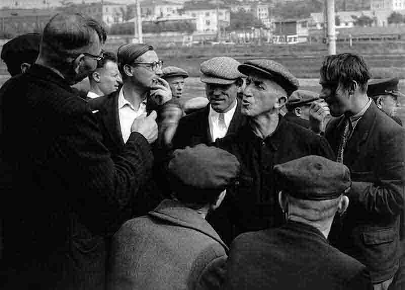 A monochrome photograph showcasing a group of soviet men engaged in conversation, standing together in a casual setting, showcasing camaraderie and lively discussion.