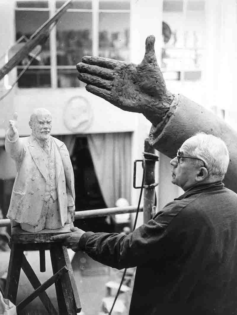 Sculptor meticulously chisels a statue of a man, showcasing dedication and artistry in his craft.