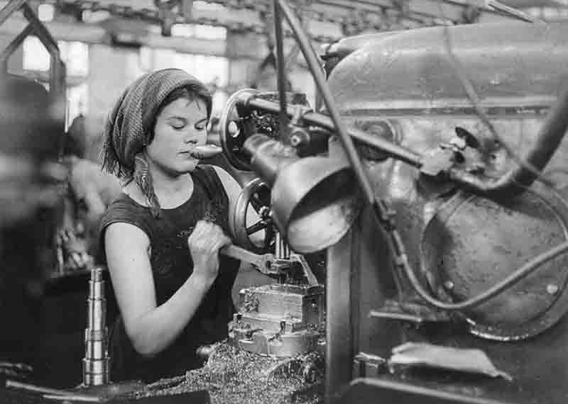 A monochrome photograph showcasing a Soviet woman engaged in operating a machine in the Stalingrad tractor factory.