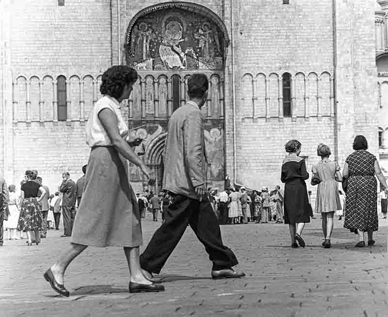 A monochrome image of individuals strolling in front of a Moscow church.