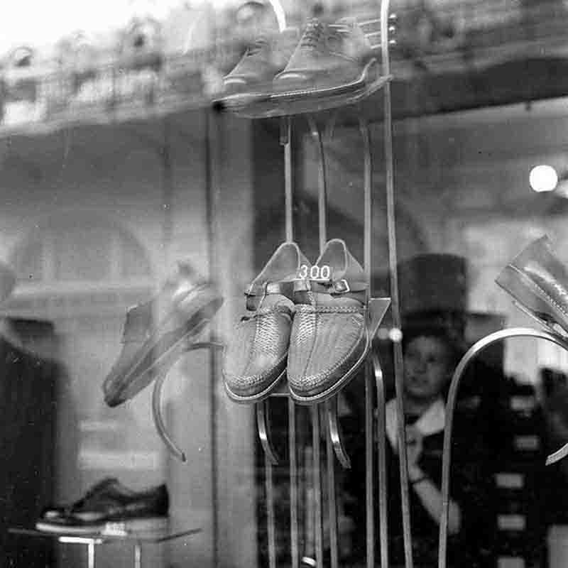 A black and white photograph showcasing a pair of shoes displayed in a store window.