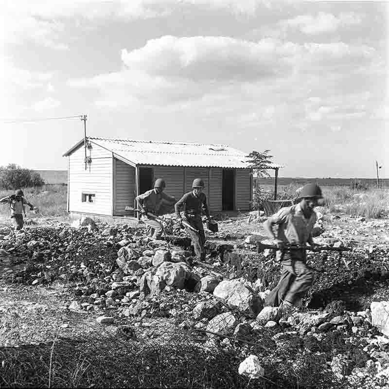 A black and white historical photograph capturing a group of soldiers of Israel Defense Forces (IDF) in combat during the Suez Crisis.