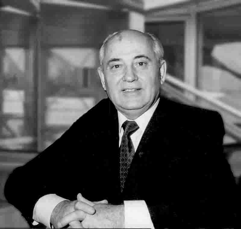 A black and white portrait of Mikhail Gorbachev, the final leader of the Soviet Union. He is shown from the chest up, wearing a dark suit, a light-colored dress shirt, and a patterned tie.