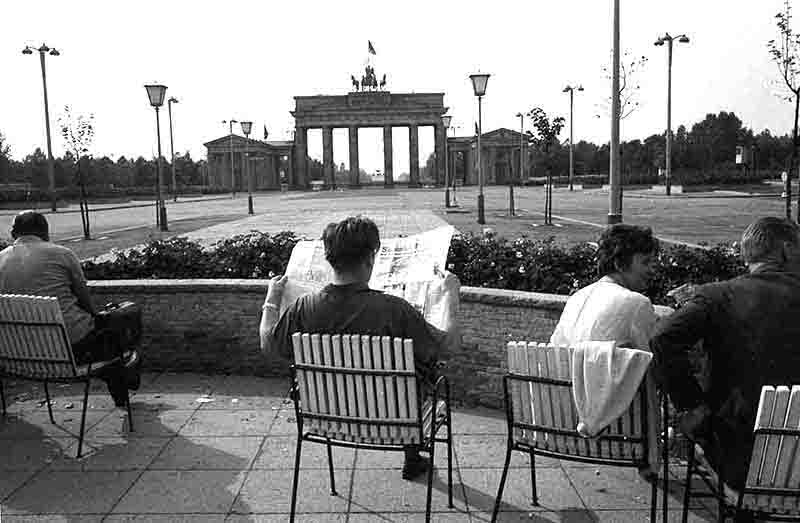 A group of people seated in chairs, enjoying the view near the iconic Brandenburg Gate in Berlin.
