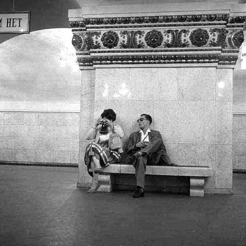 A man and woman are seated on a bench in a Moscow subway station.