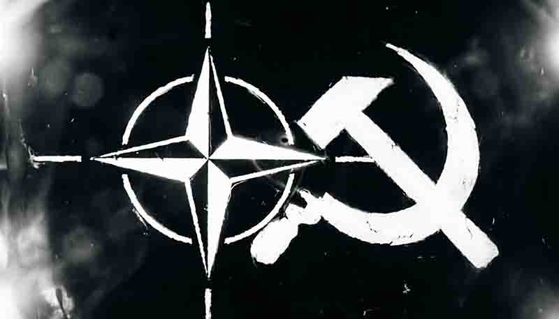 A high-contrast, black-and-white image featuring two iconic political symbols superimposed against a dark, textured background. On the left is the NATO star (a four-pointed compass rose), and on the right is the Hammer and Sickle, a symbol traditionally associated with communism and the Soviet Union.