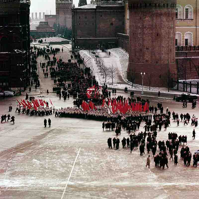 A diverse assembly of Soviet people adorned in red flags and coats, creating a striking visual of solidarity and collective spirit.