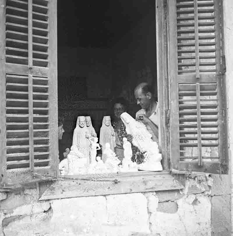 A couple stands by a window, observing a Russian Orthodox statue, embodying a serene and contemplative atmosphere.