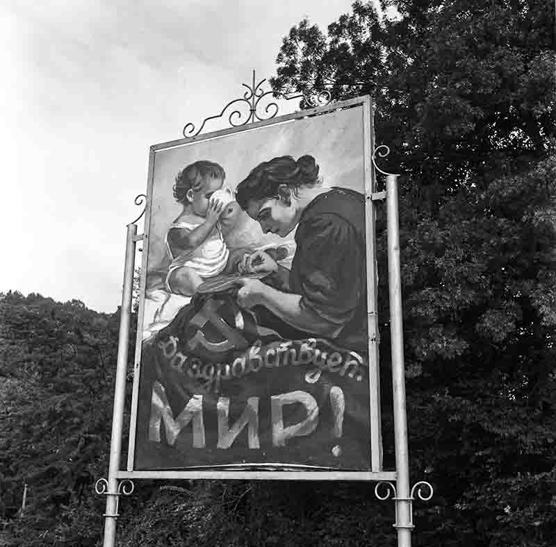 A black and white photo showcasing a soviet realism sign with a woman and child, representing themes of family and support.