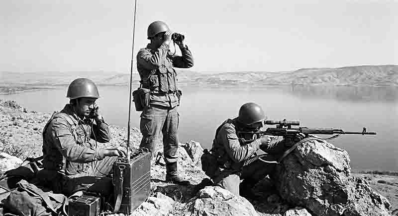 Soviet military photography from the Soviet-Afghan War (1979–1989). It depicts a specialized reconnaissance or surveillance team in the arid, mountainous terrain typical of the Afghan landscape.