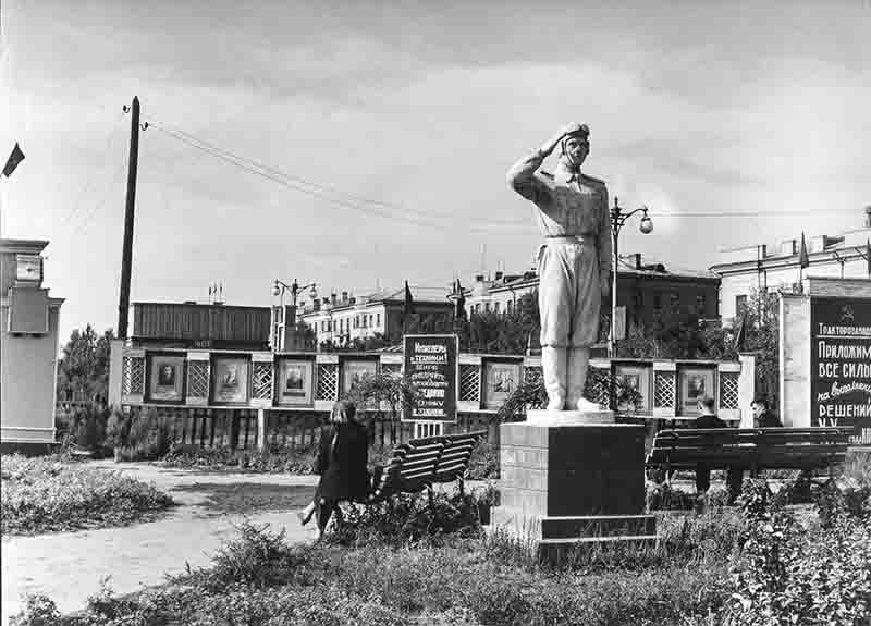 A Soviet soldier realism statue stands guard over a peaceful park.