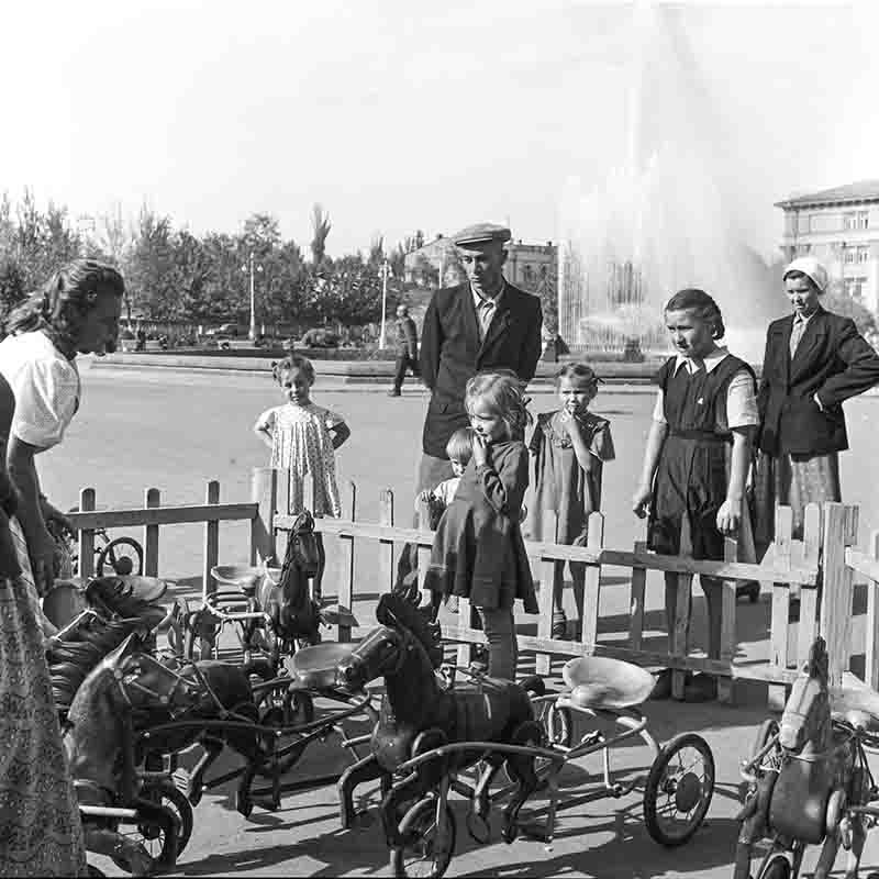 A monochrome photograph showcasing Soviet family at an outdoor market for wooden toys