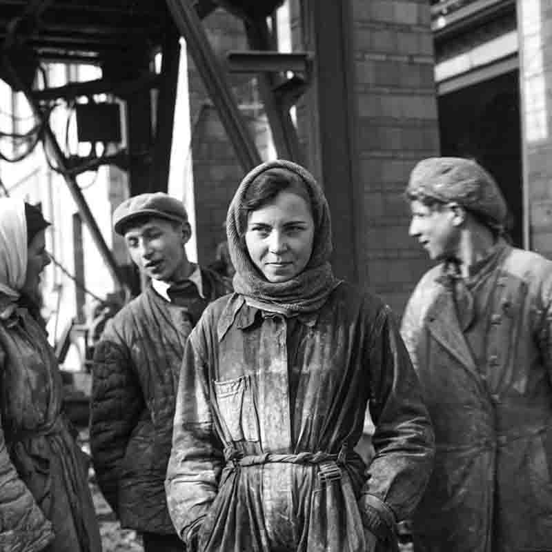 A monochrome photograph showcasing Soviet Union construction workers posing together in front of a construction site.