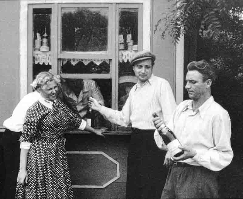 A monochrome photograph showcasing a group of people open a bottle of sparkling wine made from grapes grown on the famous Crimean peninsula.