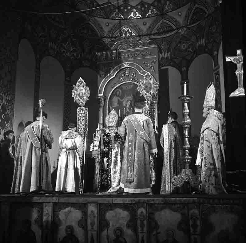 A monochrome image of a group of clergy performing a religious ceremony in an Russian Orthodox setting.