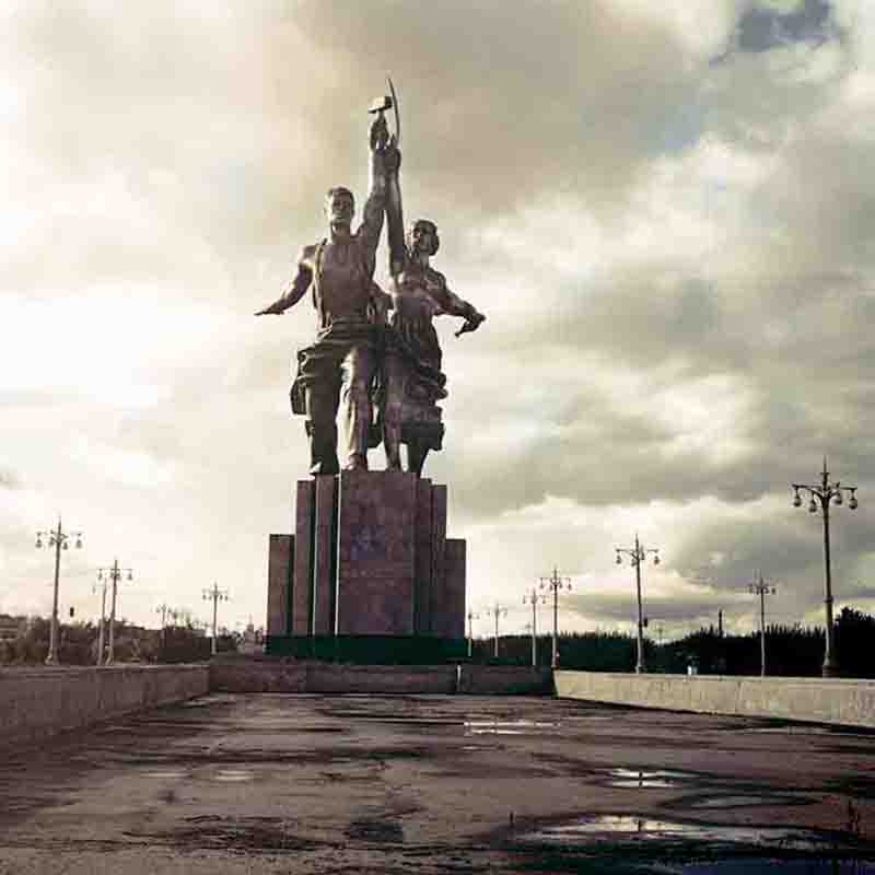 A photograph of the famous Worker and Kolkhoz Woman statue in Moscow. The monumental sculpture shows a man and a woman holding a hammer and sickle high above their heads.